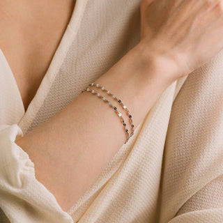 Close-up of a wrist wearing a delicate bracelet with a soft beige background