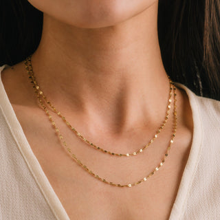 Gold chain necklace on a person wearing a beige top
