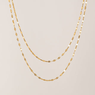 Two gold necklaces on a light gray background