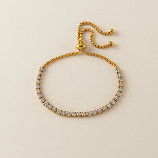 Gold bracelet with clear stones on a beige background