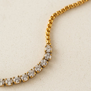 Gold necklace with clear gemstones on a beige background