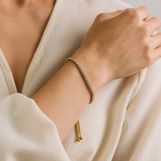 Gold bracelet on a person's wrist with a neutral background