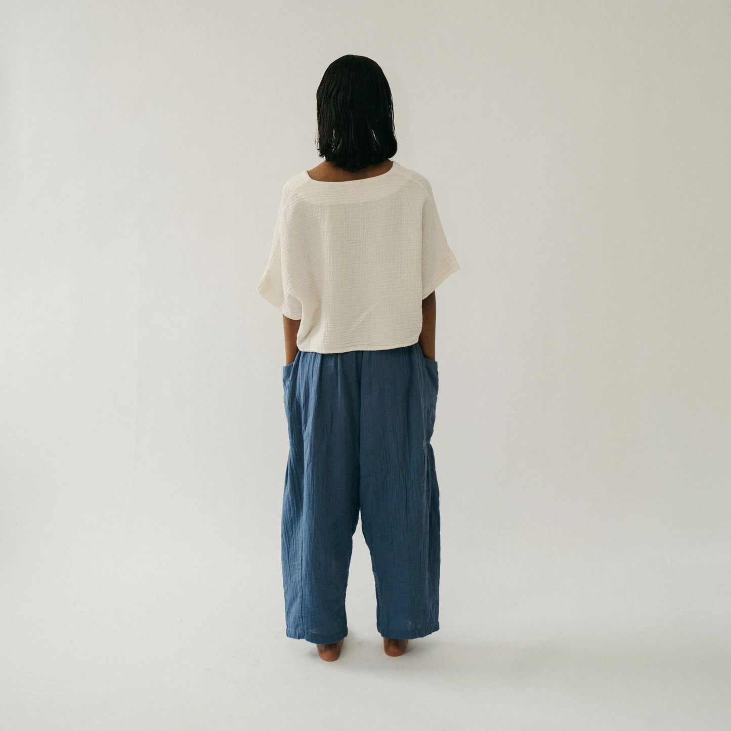 Person wearing a white top and blue pants on a plain background