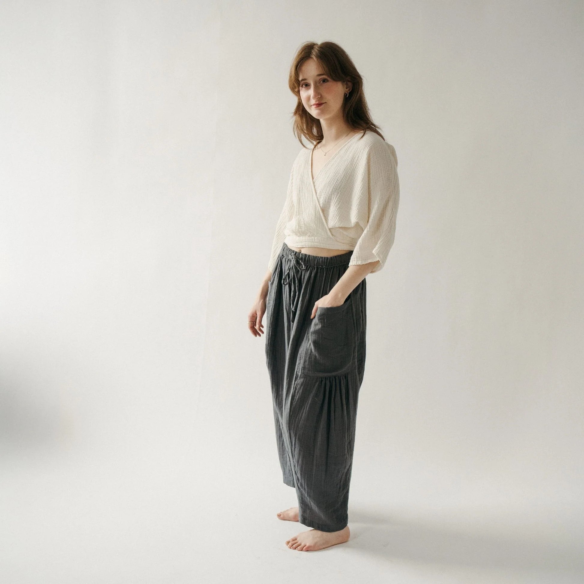 Woman wearing a white top and dark pants on a plain background