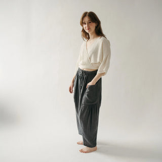 Woman wearing a white top and dark pants on a plain background