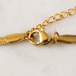 close up of the hook closure of a gold necklace