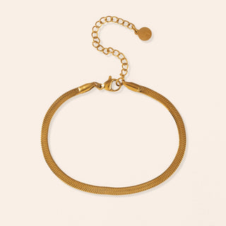 A gold bracelet laying on a table. 