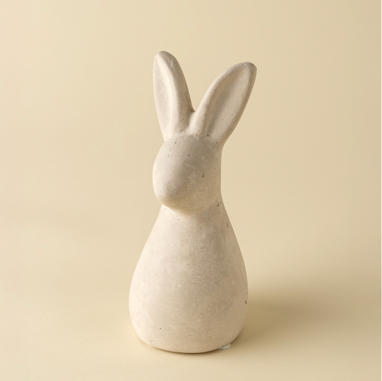 White ceramic rabbit sculpture on a beige background