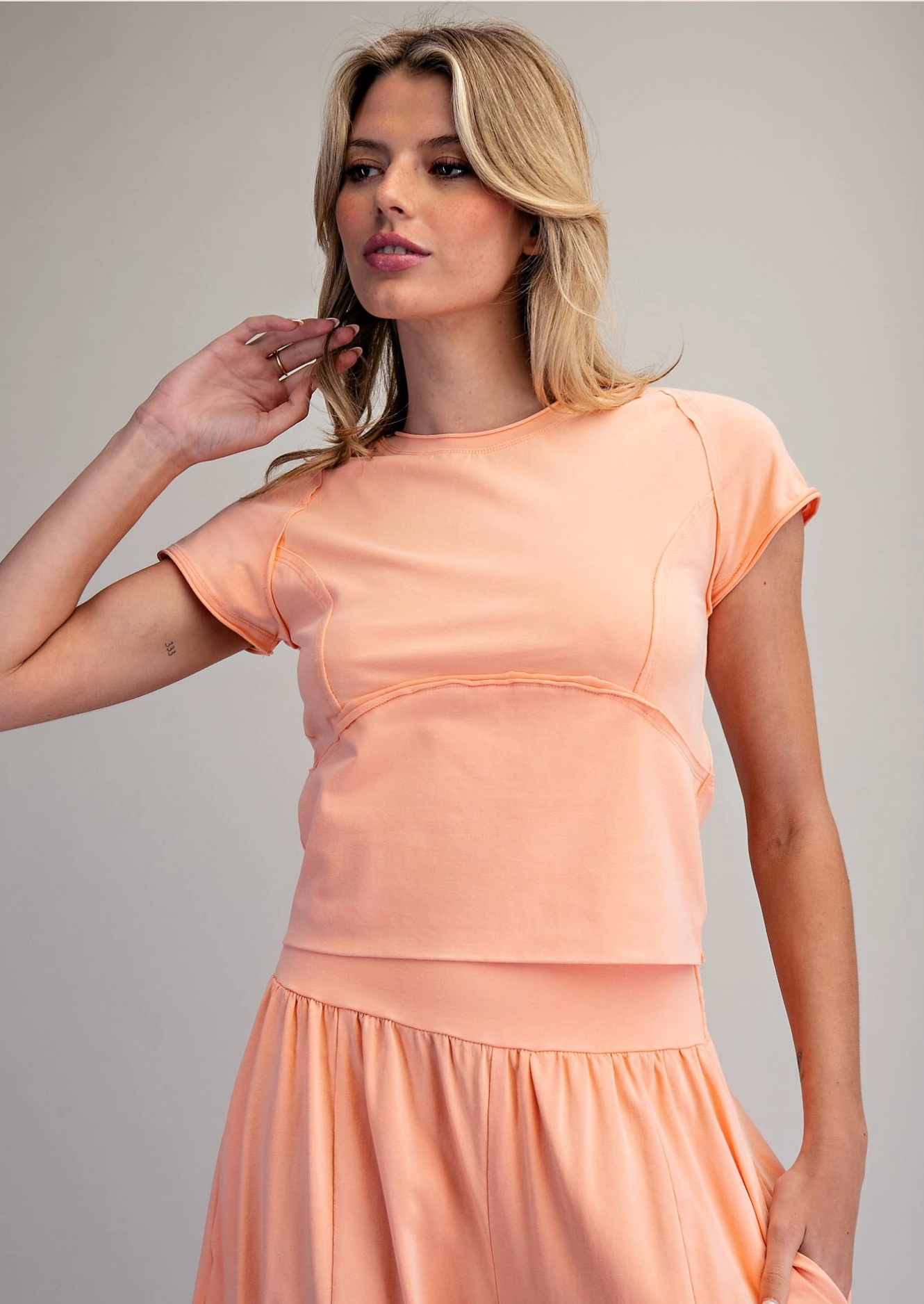 Woman wearing a peach-colored dress against a plain background