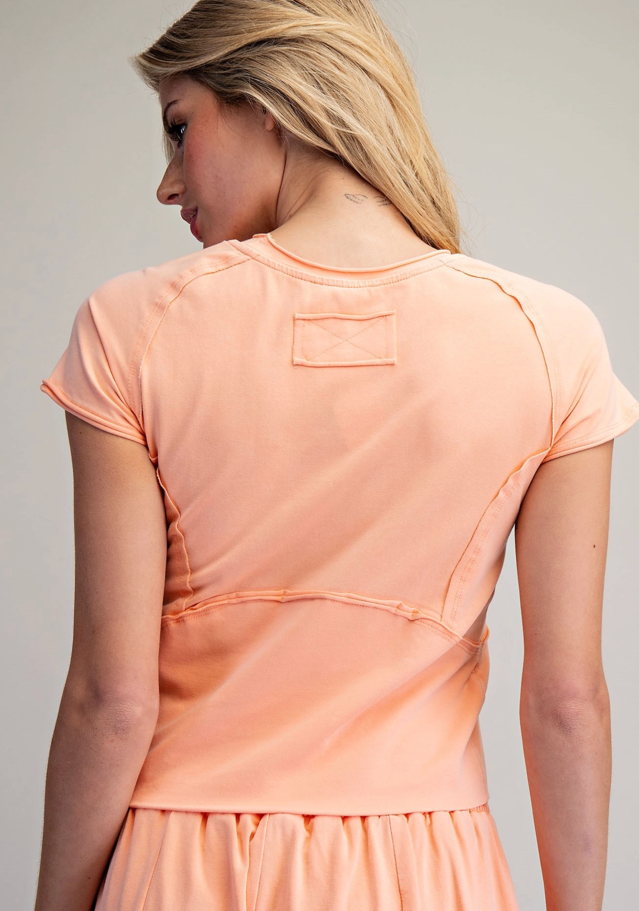Woman wearing a peach-colored matching set against a plain background