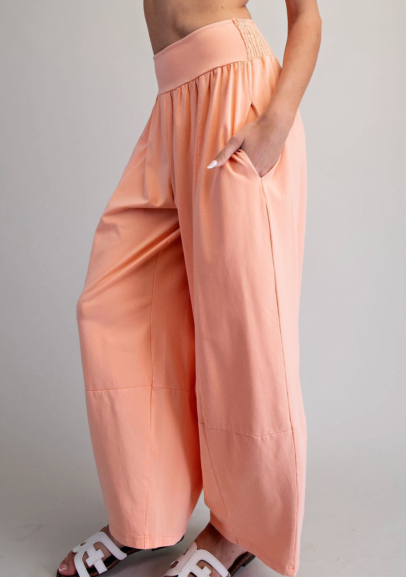 Person wearing peach-colored wide-leg pants on a plain background
