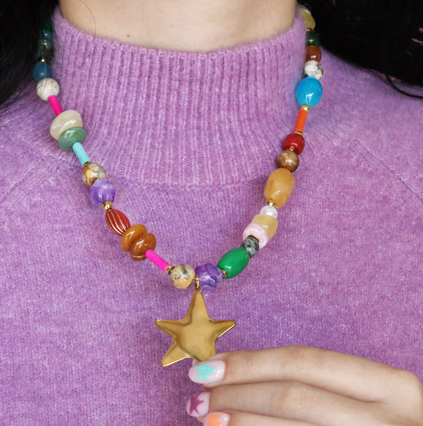 Women wearing a bright and colourful beaded necklace with a star pendant on it. 