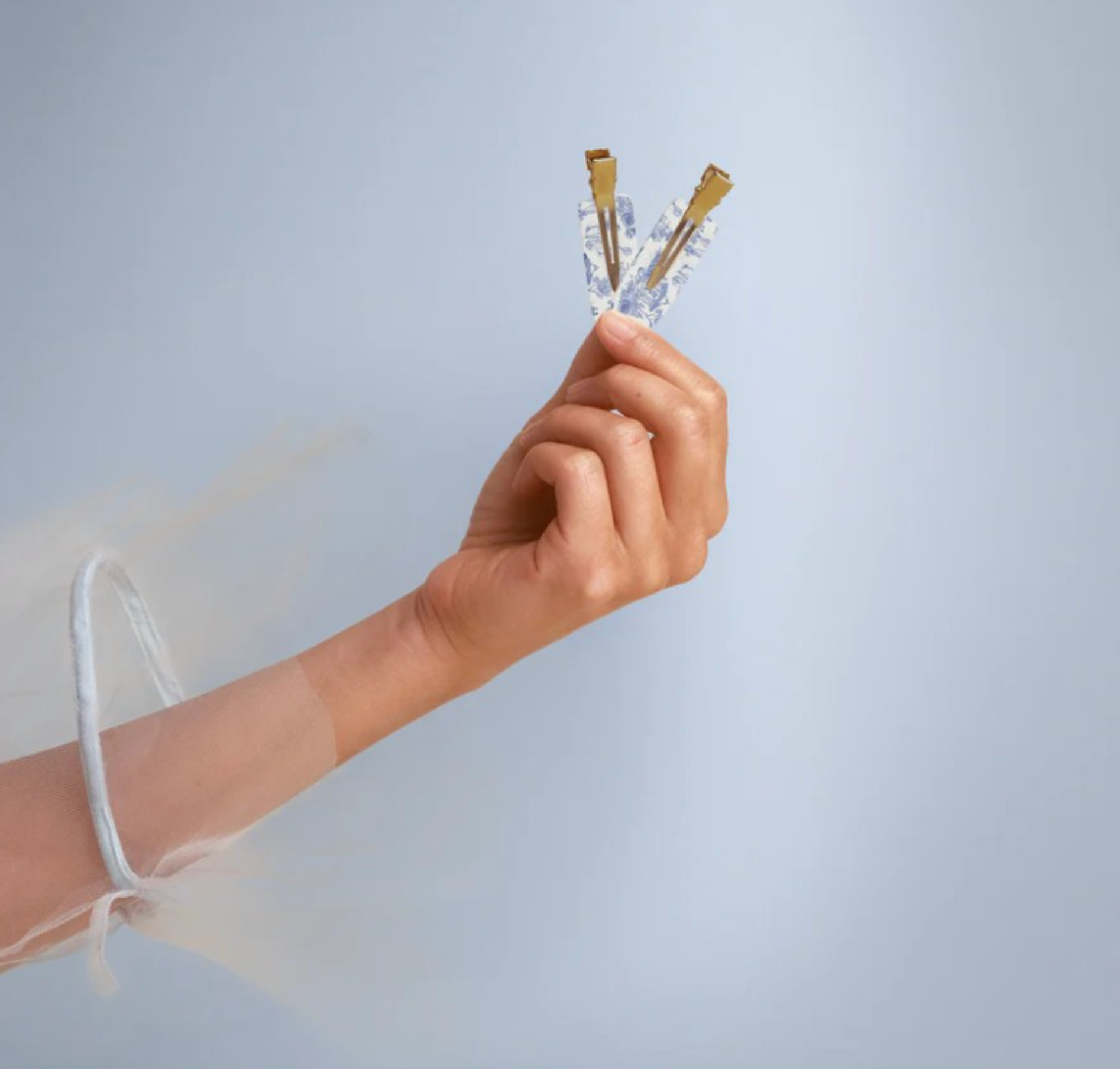 Hand holding a small object against a light gray background