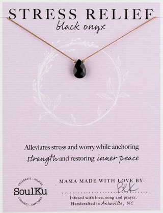 Black onyx teardrop necklace on a purple card with text about stress relief and brand information.