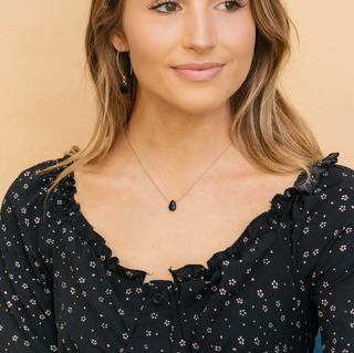 Woman wearing a black floral blouse against a beige background