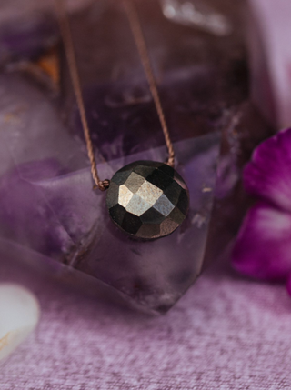 Necklace with a faceted black stone pendant on a purple floral background