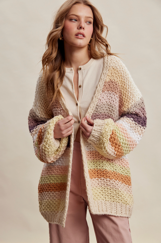 Woman wearing a colorful knitted cardigan against a beige background