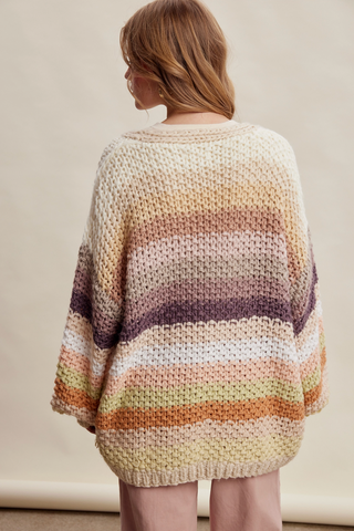 Person wearing a striped, oversized sweater against a plain background