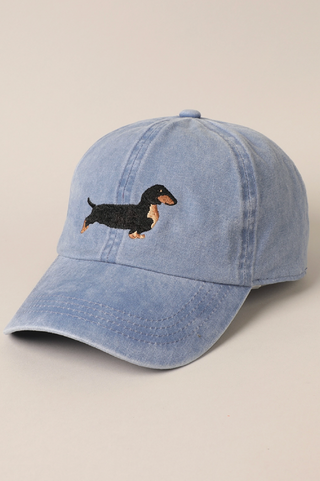 Blue denim cap with embroidered dachshund on a beige background