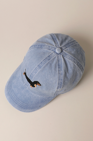 Blue denim cap with a small embroidered design on a beige background