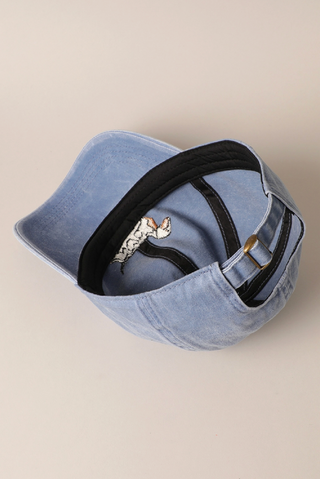 Blue denim cap with black strap on a beige background