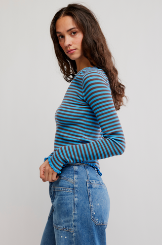 Woman wearing a blue and gray striped sweater and jeans on a plain background