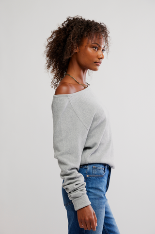 Woman wearing a gray sweater and blue jeans against a plain background