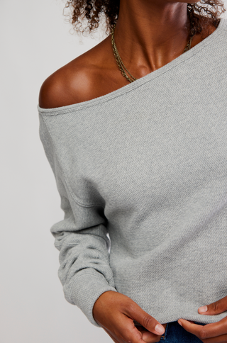 Gray off-shoulder sweater worn by a person on a plain background