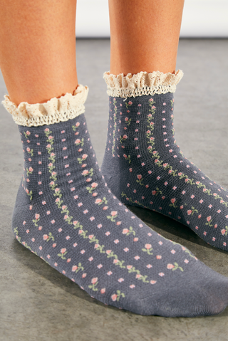 Women wearing floral ruffle sock sitting on the ground.
