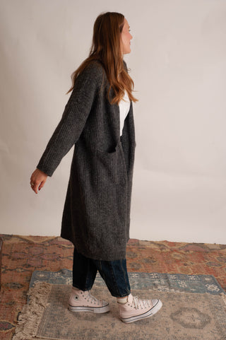 Women wearing a long charcoal cardigan against a neutral photo backdrop. 