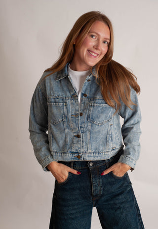 Women modelling a denim jacket against a neutral photo background. 