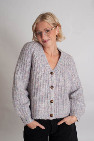 Women modelling a purple confetti cardigan against a neutral photo back drop. 