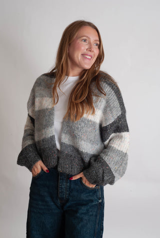 Women modelling a grey striped cardigan against a neutral photo backdrop. 