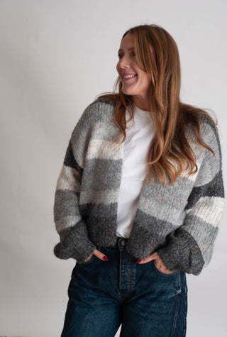 Women modelling a grey striped cardigan against a neutral photo backdrop. 