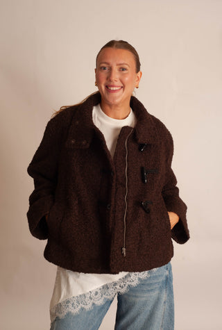 Women modelling a brown sherpa teddy coat against a neutral photo backdrop. 