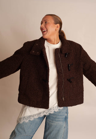 Women modelling a brown sherpa teddy coat against a neutral photo backdrop. 