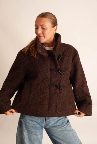 Women modelling a brown sherpa teddy coat against a neutral photo backdrop. 