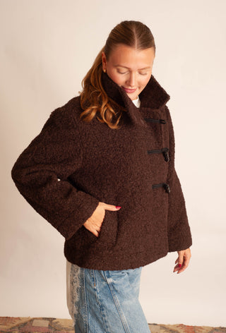 Women modelling a brown sherpa teddy coat against a neutral photo backdrop. 