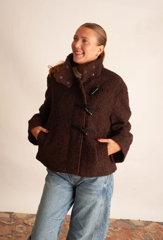 Women modelling a brown sherpa teddy coat against a neutral photo backdrop. 