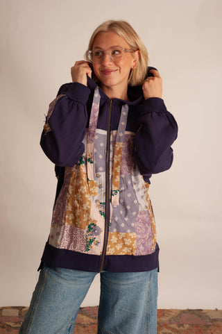 Women modelling a purple boho hoodie in front a neutral photo backdrop. 