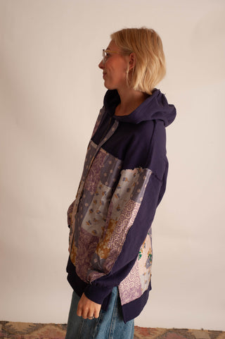 Women modelling a purple boho hoodie in front a neutral photo backdrop. 