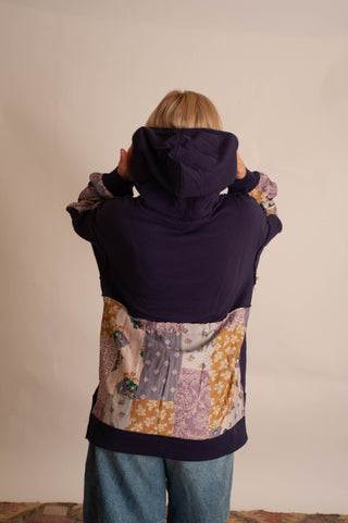 Women modelling a purple boho hoodie in front a neutral photo backdrop. 