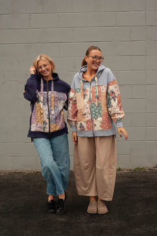 two women wearing matching boho hoodies standing in front of a brick wall. 