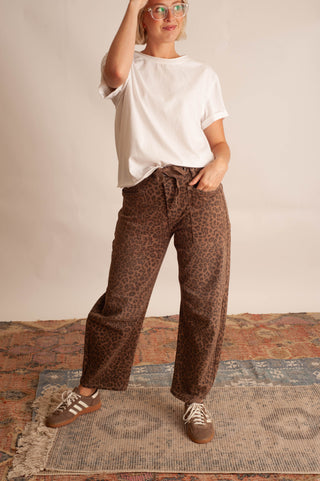 Women modelling a white t-shirt and leopard barrel pants against a neutral photo backdrop.