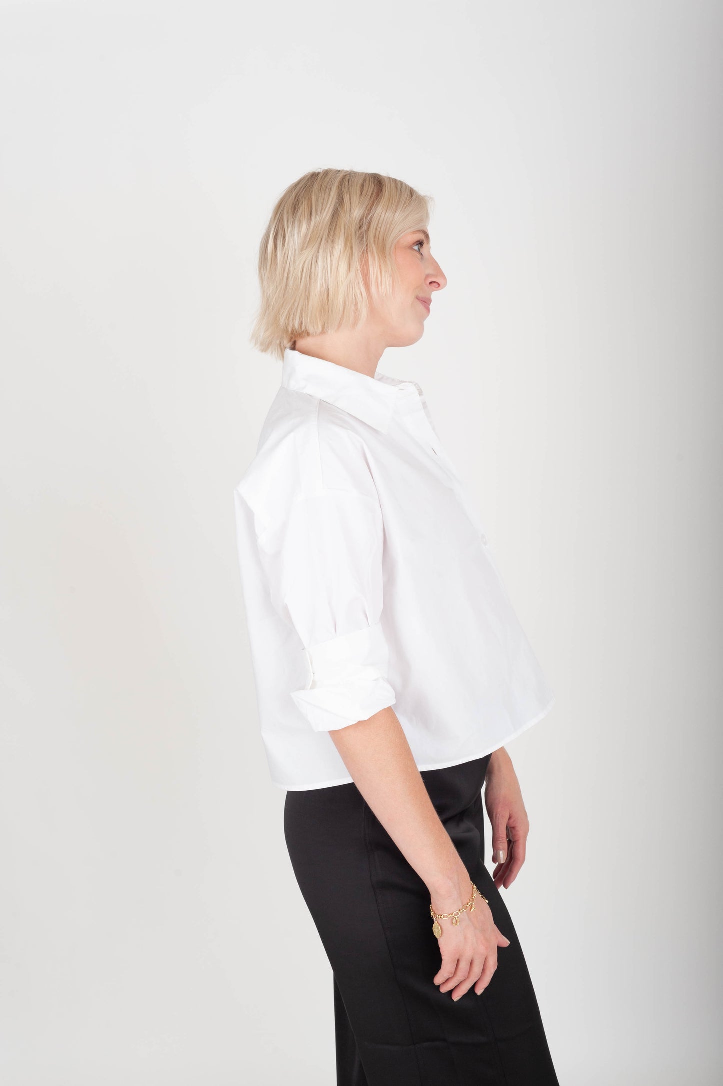 Woman wearing a white shirt and black pants against a white background