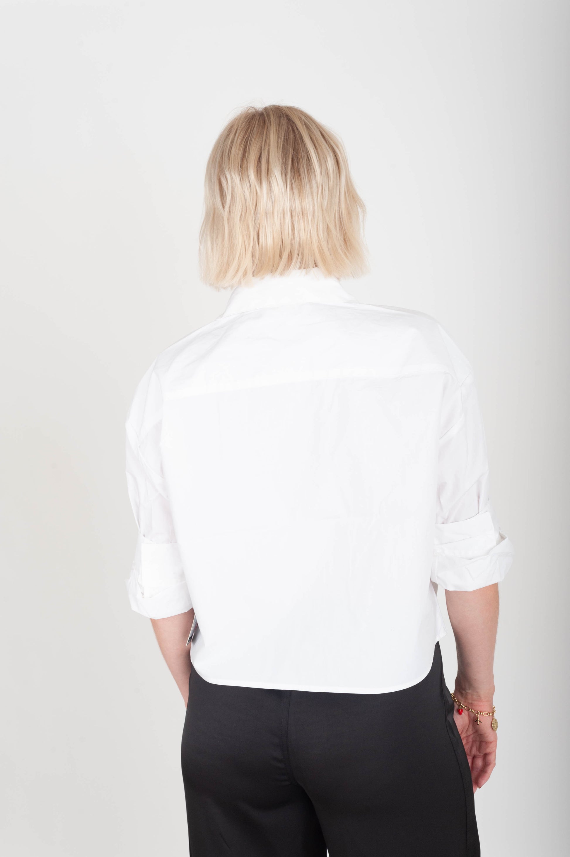 Person wearing a white shirt and black pants on a plain background