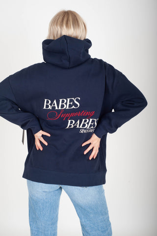 Navy hoodie with 'Babes Supporting Babes' text on the back, worn by a person.