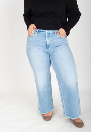 Person wearing light blue jeans and a black top on a white background