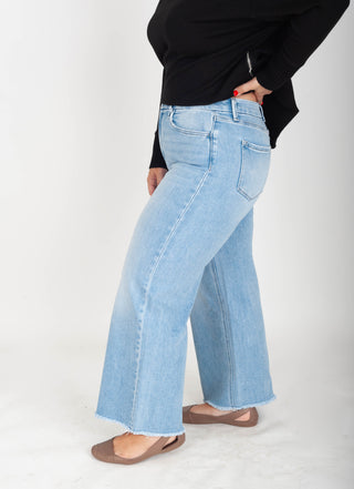 Person wearing light blue flared jeans on a white background