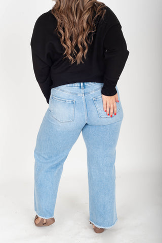 Person wearing light blue jeans and a black top on a white background